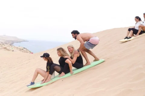 Voyageurs découvrant le sandboarding sur une dune