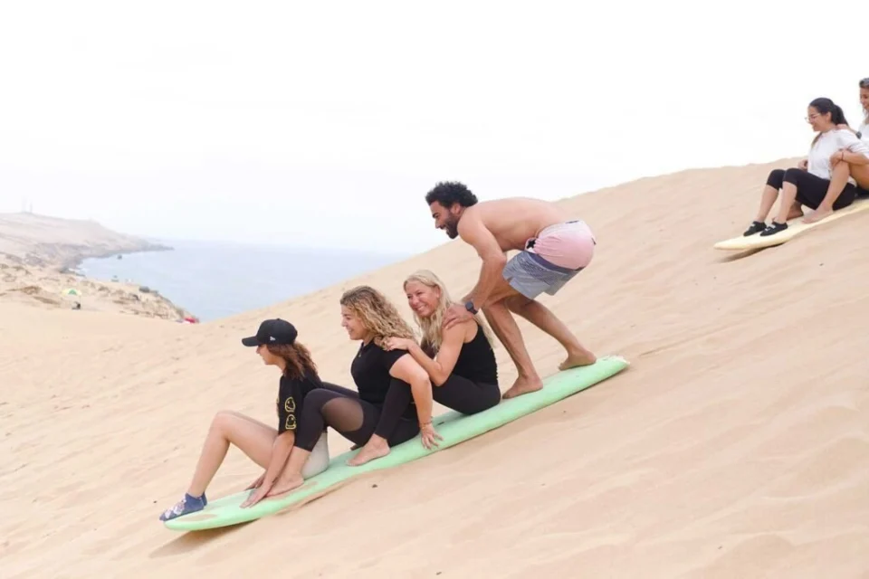 Voyageurs découvrant le sandboarding sur une dune